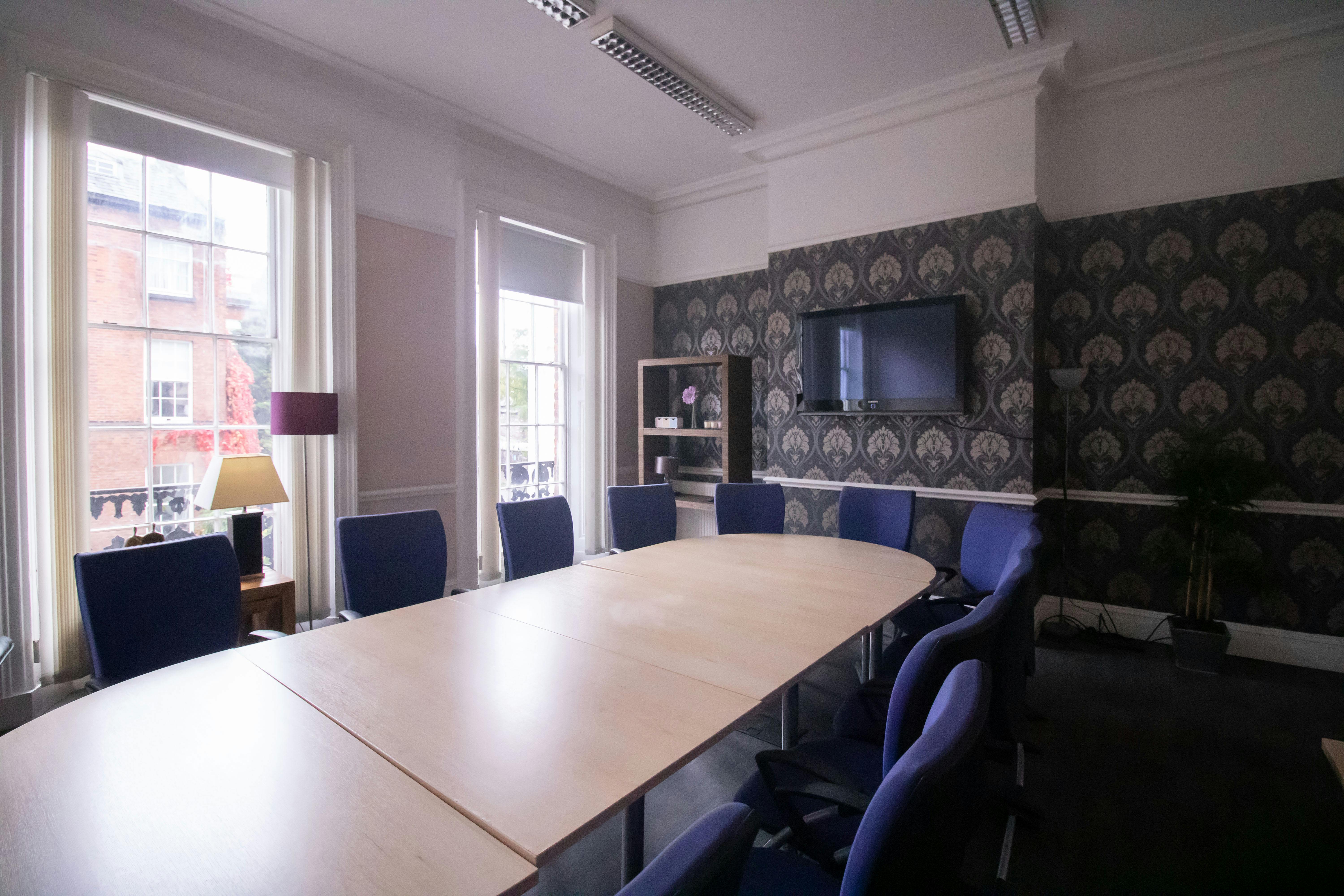 Elegant meeting room with oval table and blue chairs, perfect for professional gatherings.