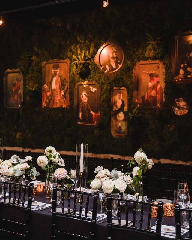 Elegant event space with moss wall and vintage portraits for upscale gatherings.