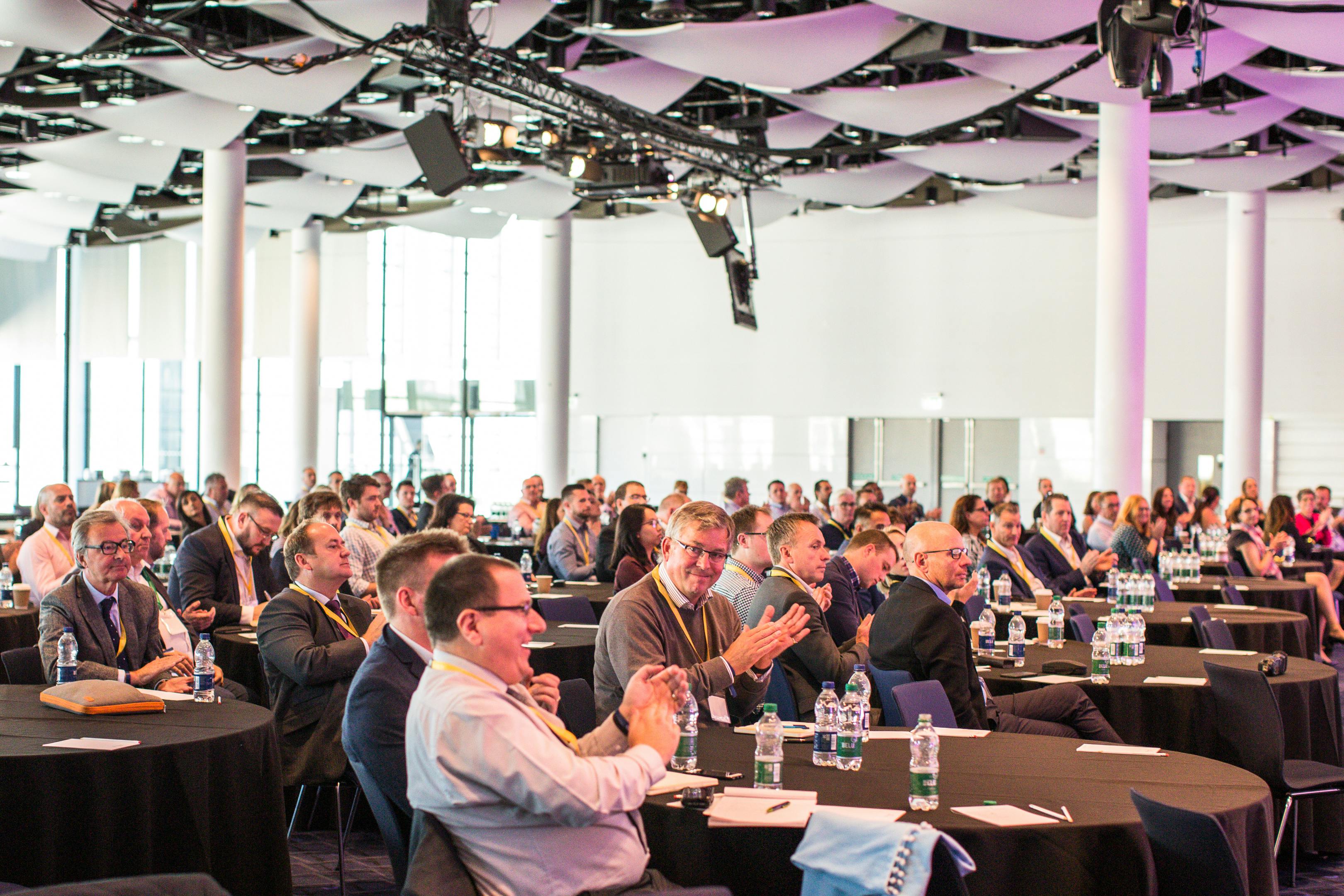 Great Hall at Wembley Stadium during an engaging conference with round tables.