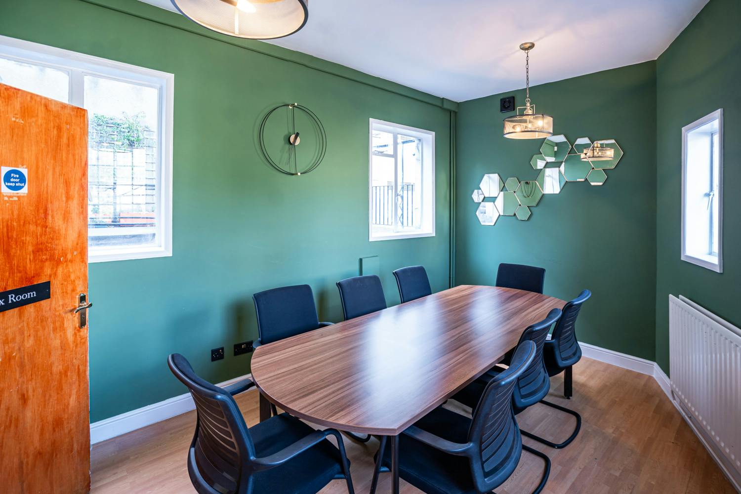 Modern meeting room in Conway Hall with wooden table and green wall, perfect for brainstorming.