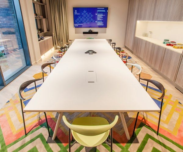 Modern conference room with sleek table and colorful chairs for collaborative meetings.