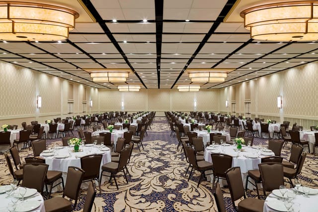 Spacious Delta by Marriott banquet hall with elegant round tables for weddings and conferences.