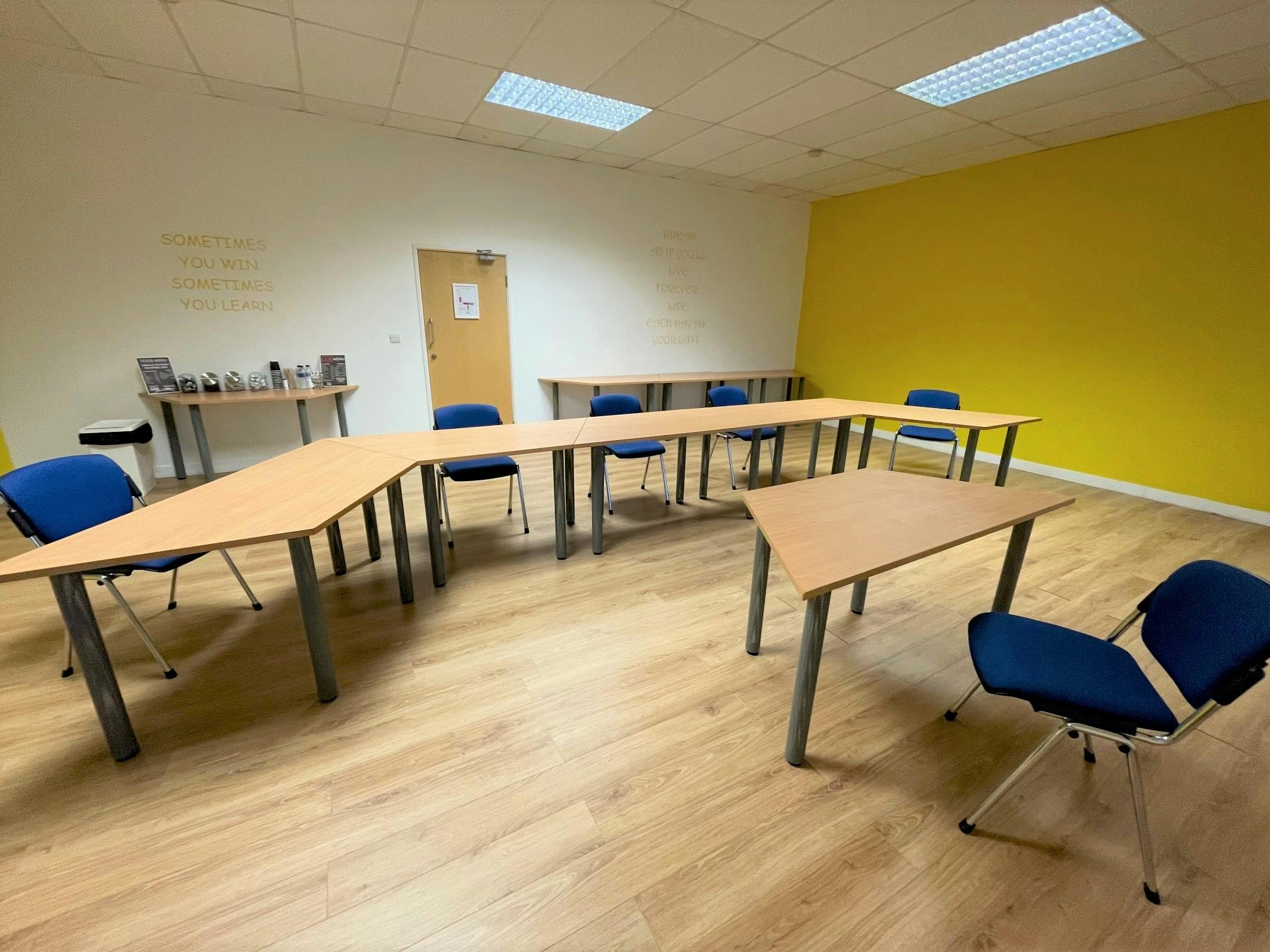 Versatile yellow meeting room with U-shaped tables for workshops and brainstorming sessions.