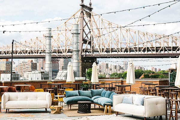 Stylish outdoor corporate event space with Queensboro Bridge backdrop and ambient lighting.
