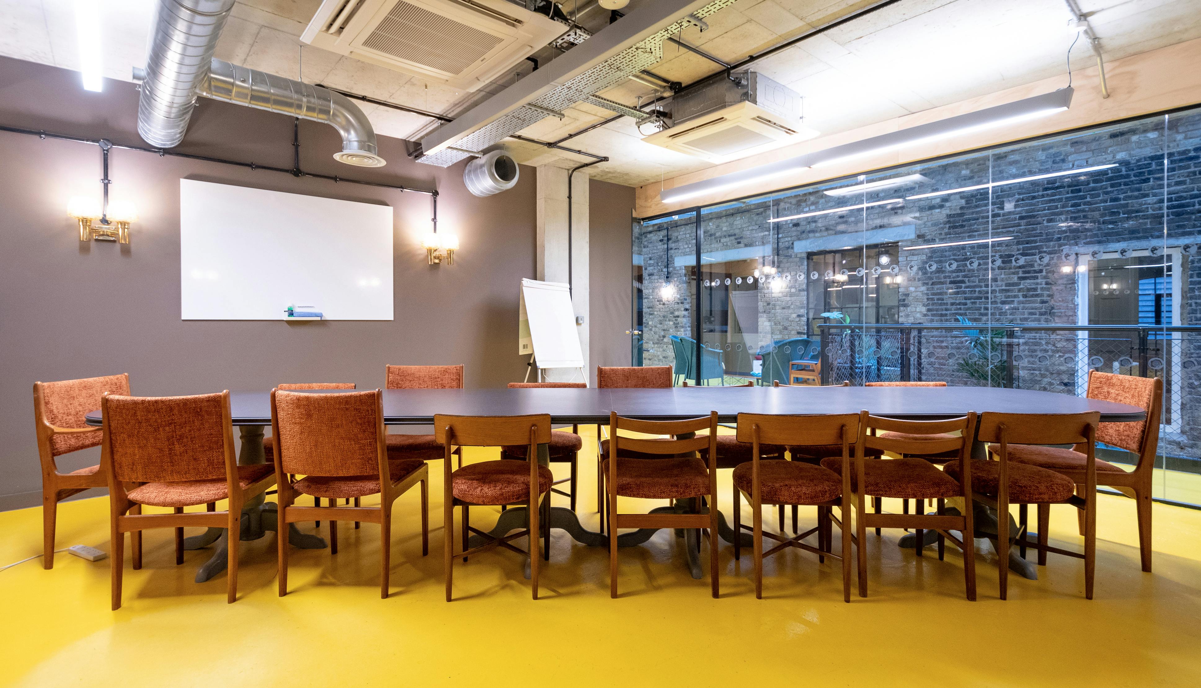 Modern meeting room with large table, bright yellow flooring for collaborative events.