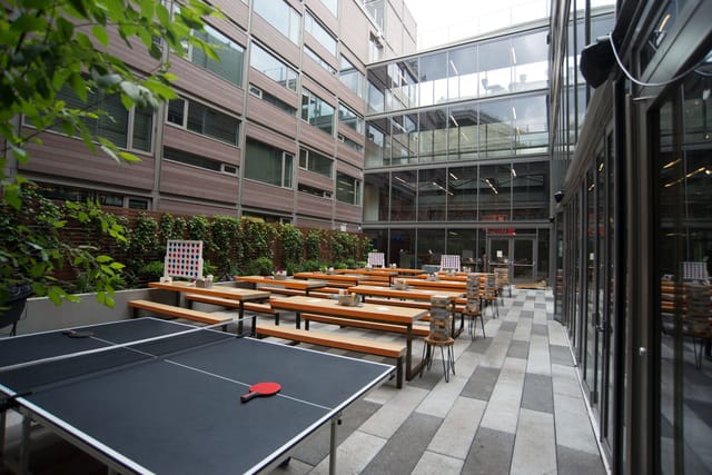 Outdoor event space at Clinton Hall, featuring communal tables and ping pong for networking.