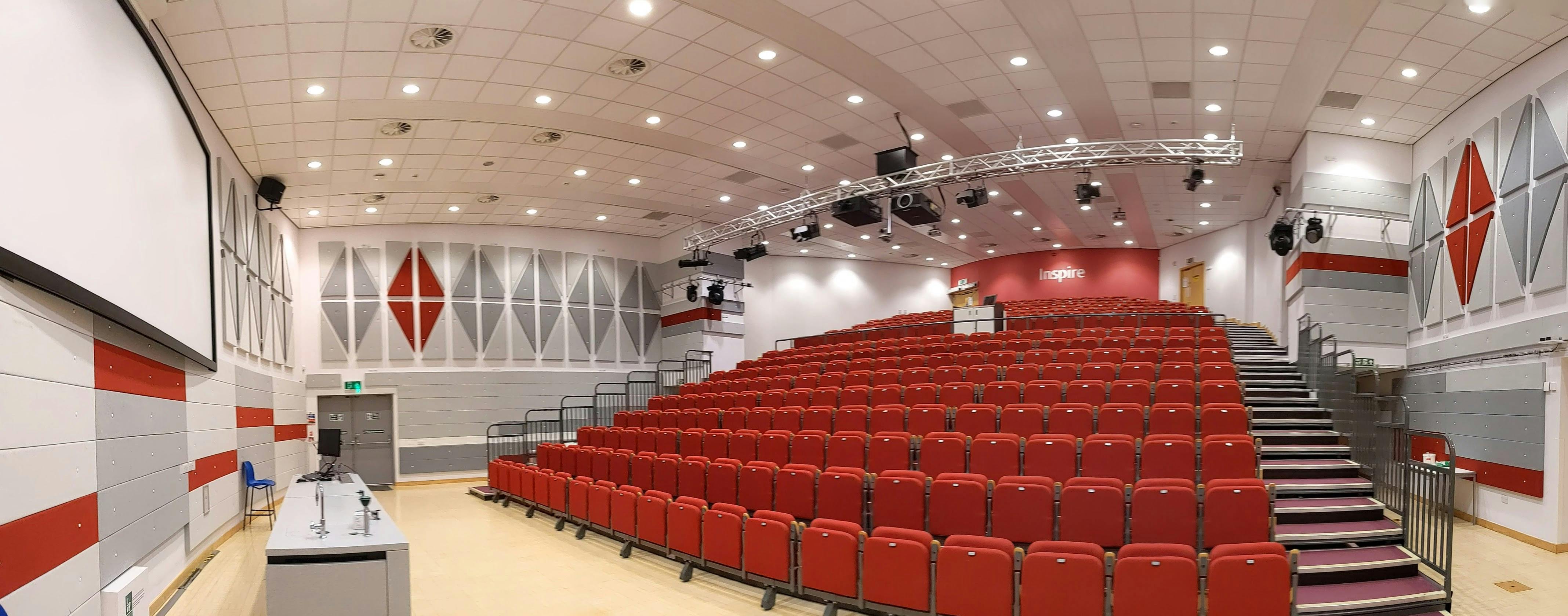 Lecture theatre with tiered red seating, perfect for conferences and presentations.