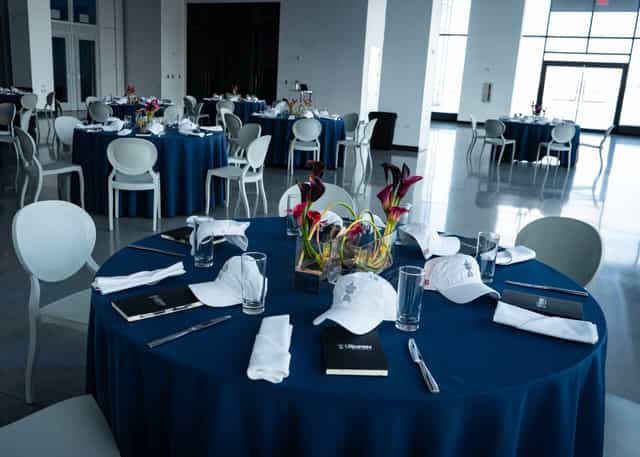 Elegant event space with navy blue linens and floral centerpieces for networking.