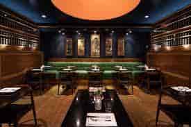 Stylish private dining room with dark wood accents and green seating for events.