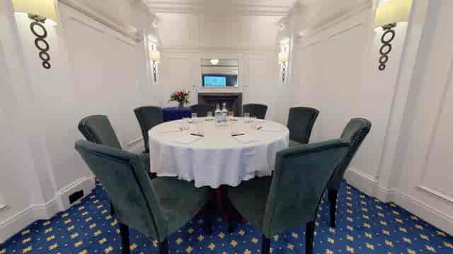President Suite meeting room with round table, plush chairs for intimate events.