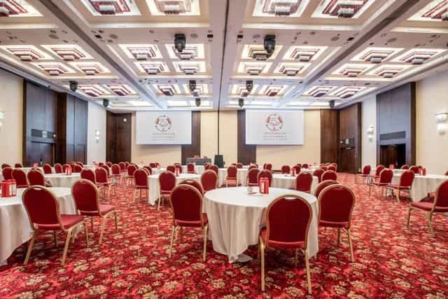 Kingdom Suite at Millennium Gloucester: elegant conference venue with round tables and screens.