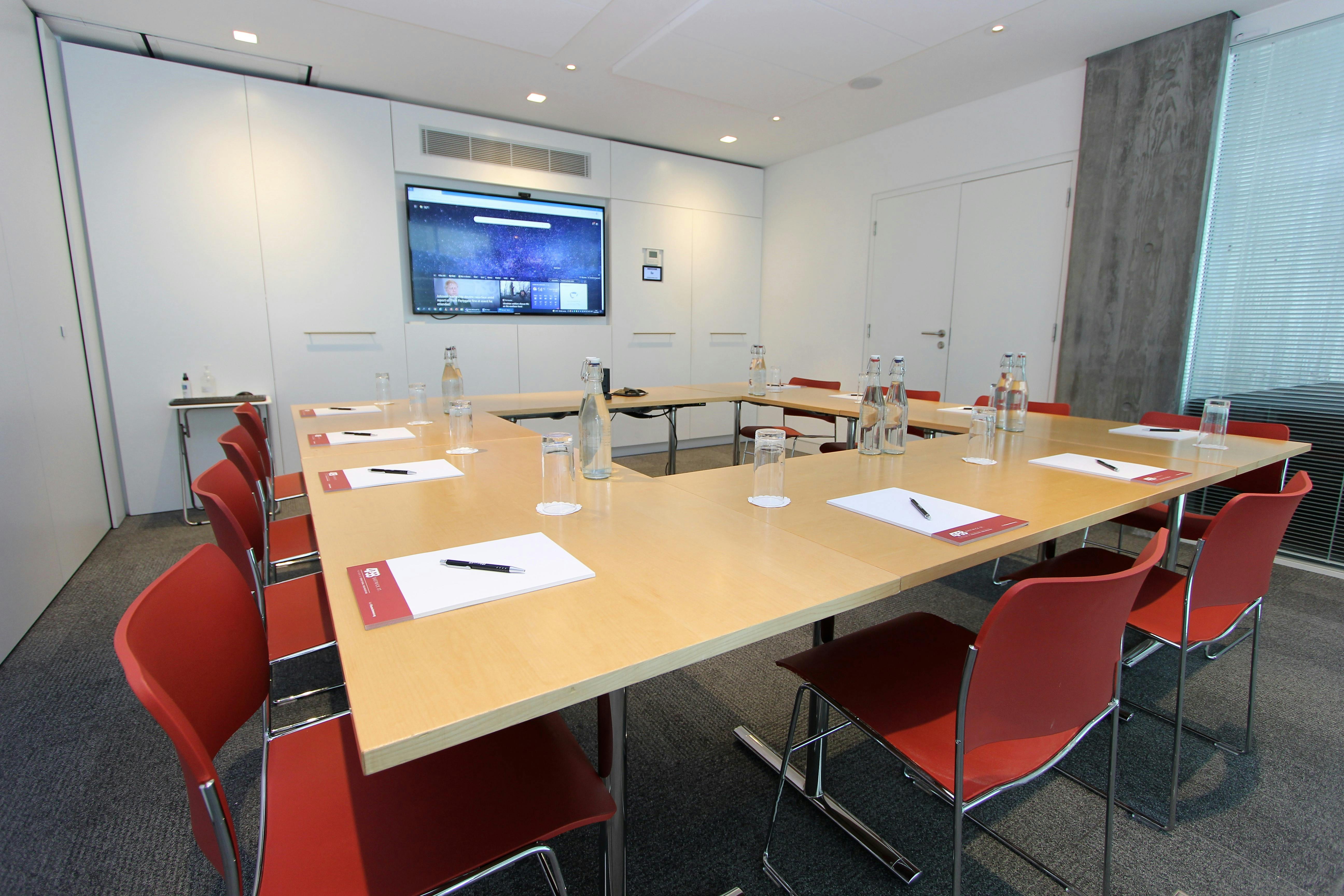 Modern meeting room with long table, ready for professional gathering and presentations.