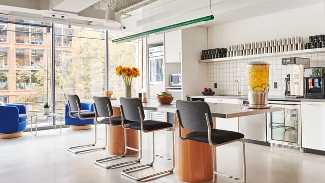 Modern kitchen at WeWork 1701, ideal for networking events with bar seating and sunflowers.