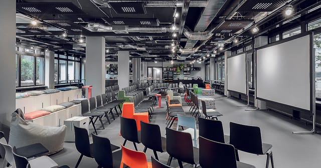Versatile event space with colorful chairs for dynamic meetings in Frankfurt.