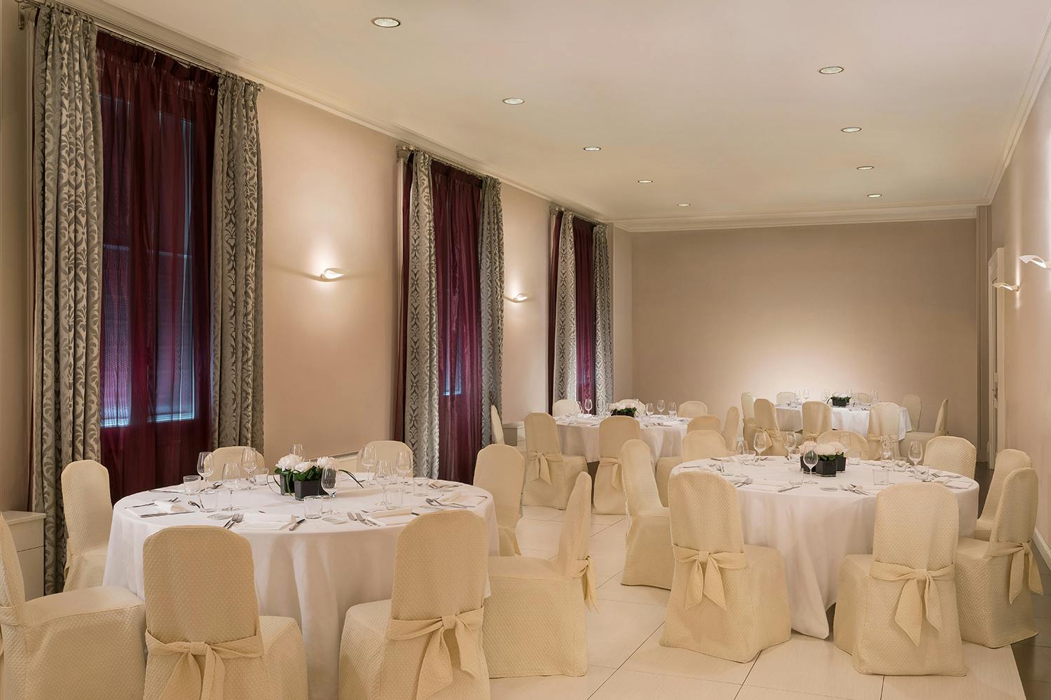 Elegant event space at Sheraton Diana Majestic, Milan with round tables and soft lighting.