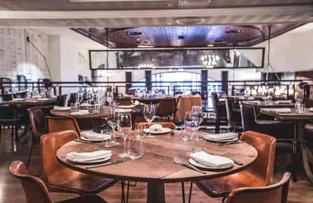Stylish restaurant setting with round wooden table for corporate dinners and gatherings.