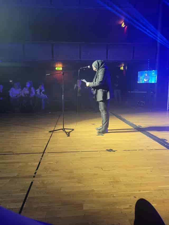 Speaker at Stratford Youth Zone: intimate hybrid event with spotlight in a low-lit ballroom.
