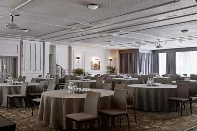 Versatile meeting room with round tables, ideal for workshops and conferences.