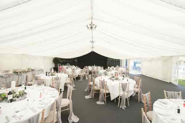 Elegant event tent at Cave Hotels, featuring round tables and floral centerpieces for weddings.