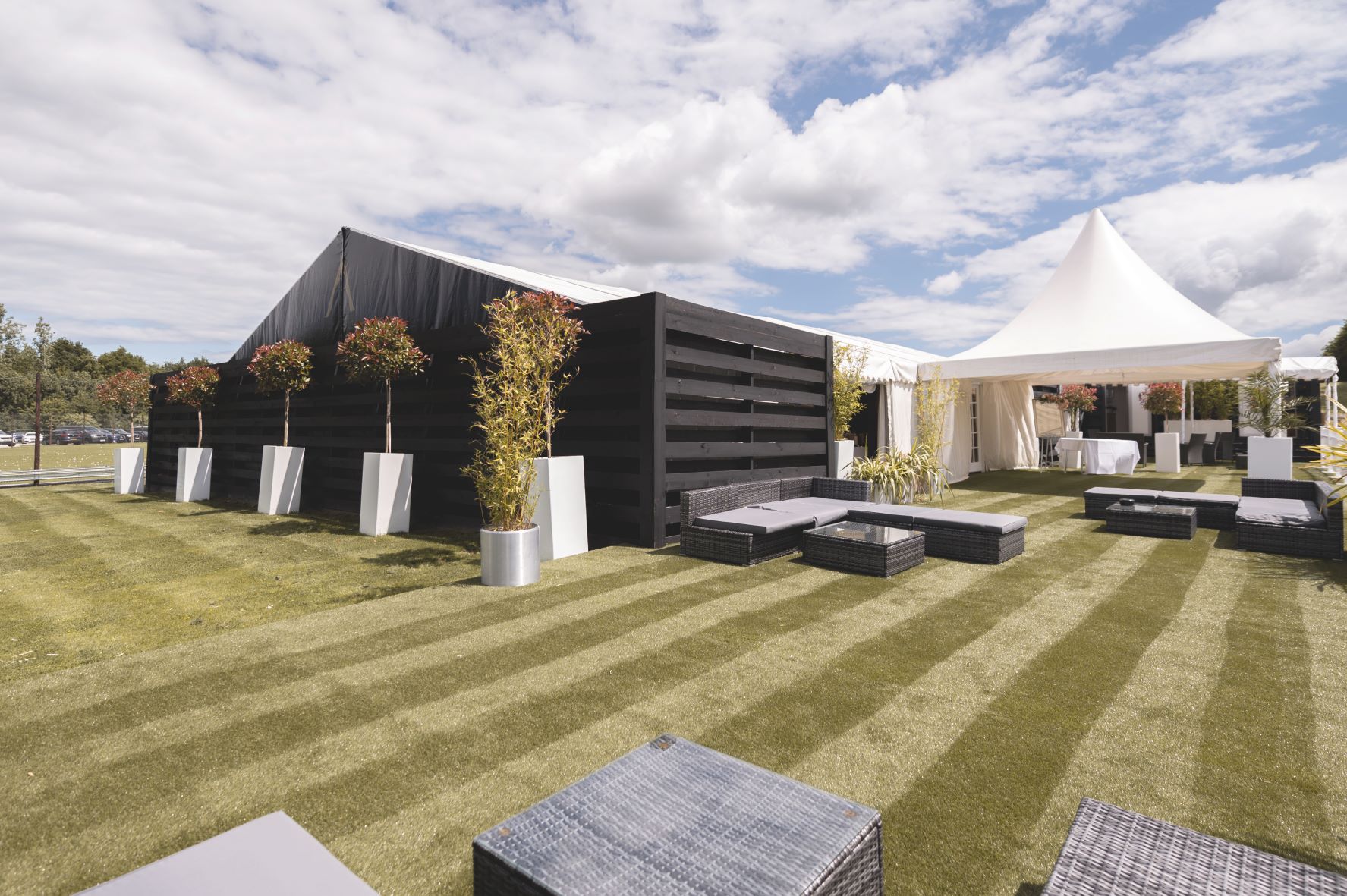 Outdoor event space with sleek black tent and white marquee at Cave Hotels Resort. - Banner