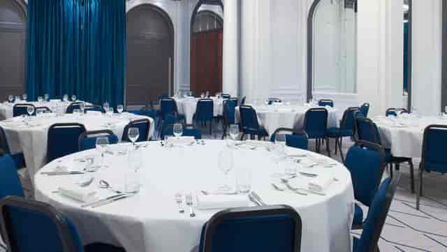 Elegant banquet space at Vendôme, Paris with round tables and blue chairs for events.