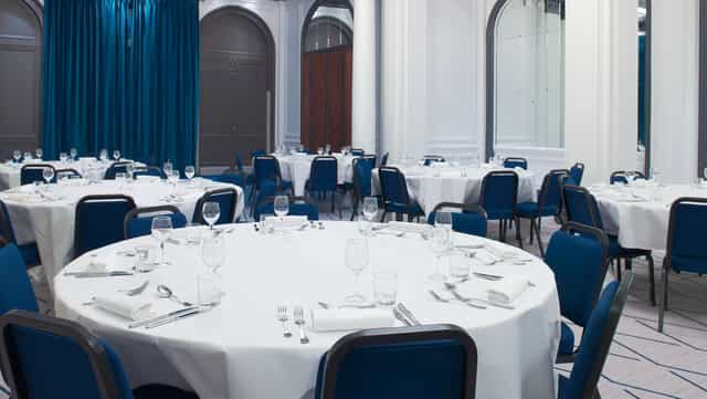 Elegant banquet space at Vendôme, Paris with round tables and blue chairs for events.