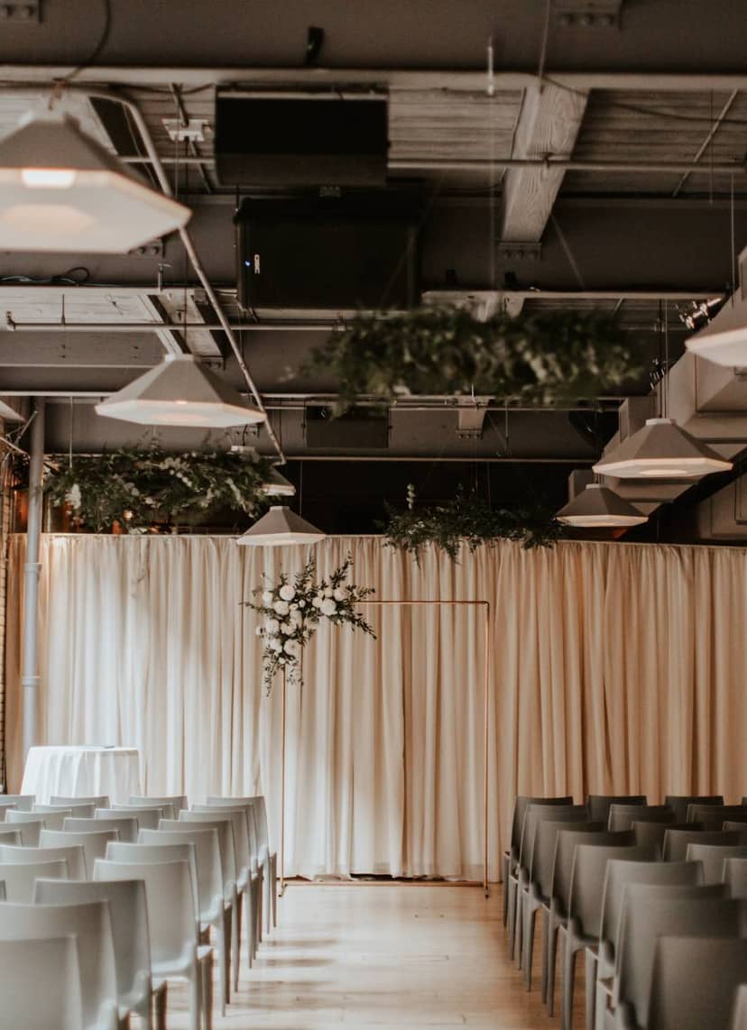 Elegant event space with drapery and floral arrangements, perfect for weddings or corporate events.