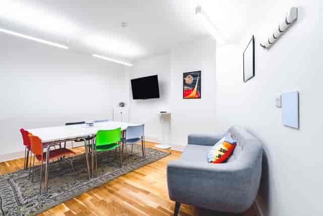 Modern meeting room with sleek table, colorful chairs for collaborative events.