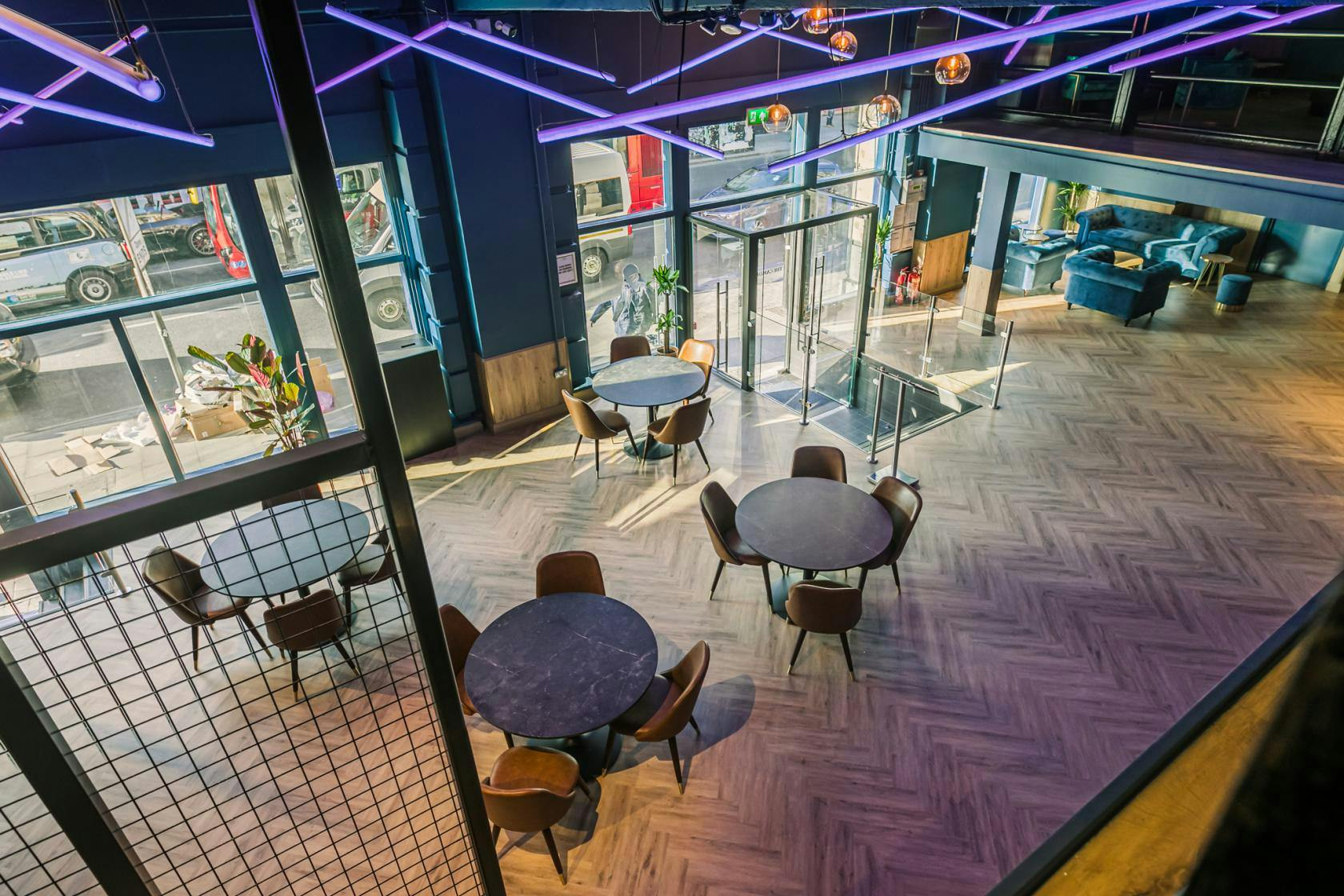 Modern event space at The Mezzanine, featuring stylish round tables and vibrant lighting.