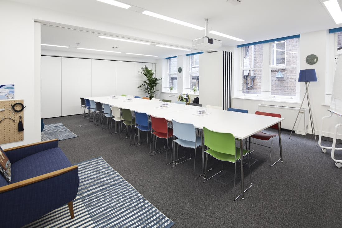 Modern meeting room with white table and colorful chairs for creative collaboration events.