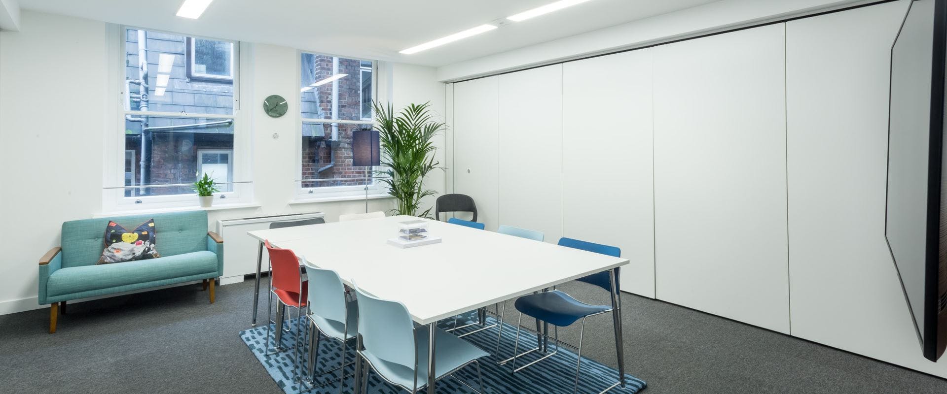 Modern meeting room with white table and colorful chairs, perfect for brainstorming sessions.