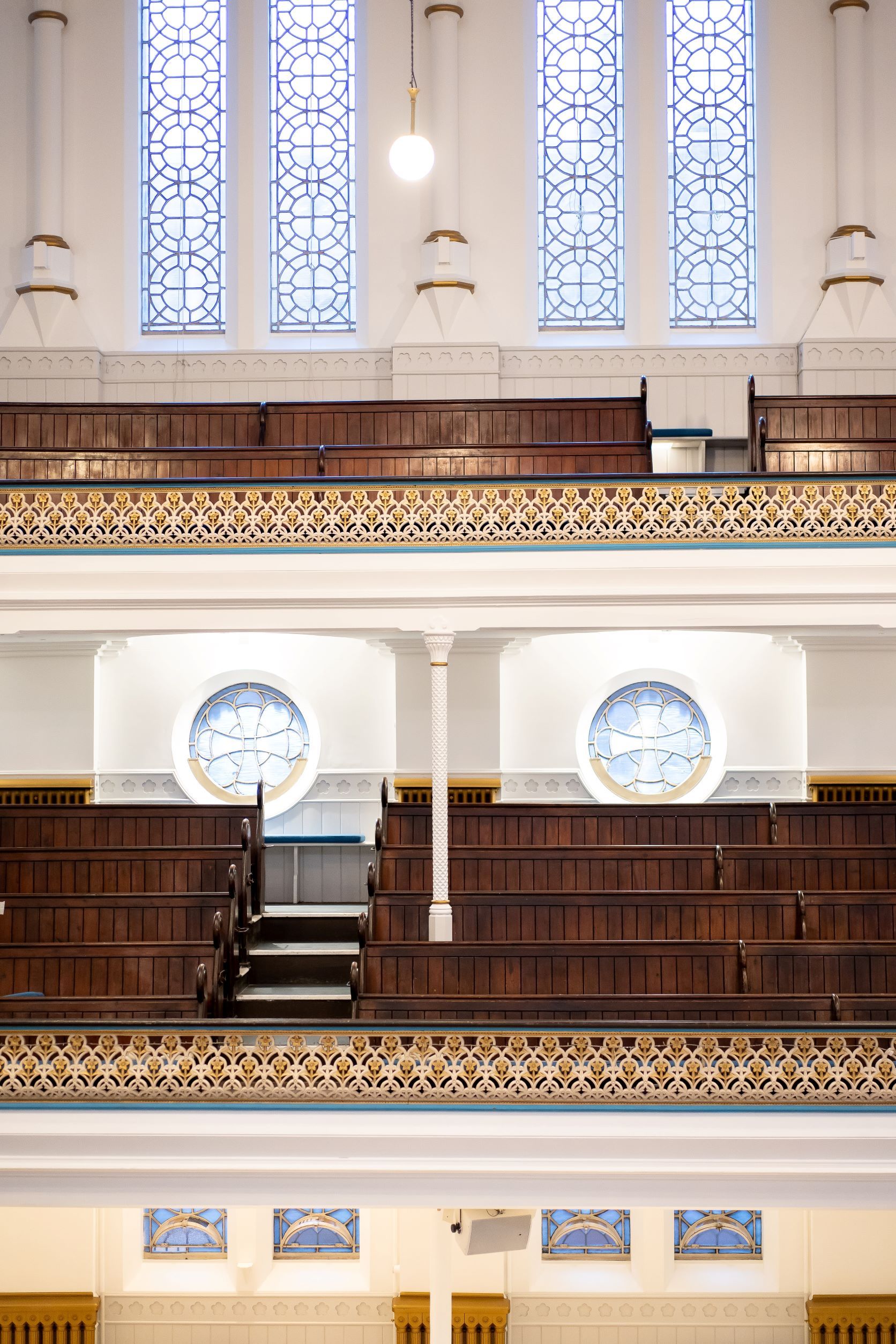 Elegant Westminster Chapel auditorium with wooden pews and stained glass for events. - Banner