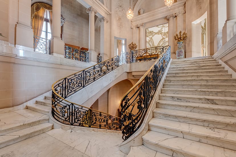 Elegant staircase with wrought-iron railings in upscale event venue, perfect for receptions.