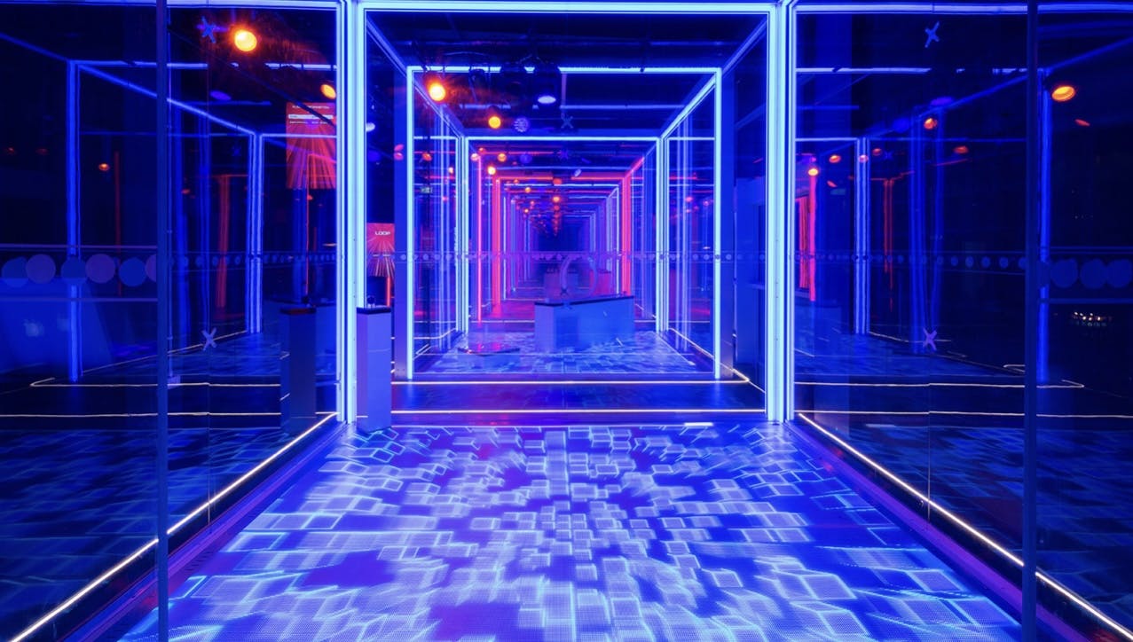 The CUBE Live Experience event space with dynamic blue and purple lighting.