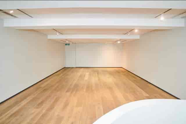 Versatile blank canvas event space with natural light and wooden flooring for meetings.
