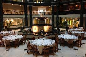 Elegant event space with round tables and central fountain for weddings and corporate gatherings.