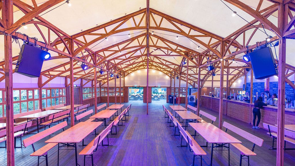 Spacious event venue with wooden beams, ideal for gatherings and performances.