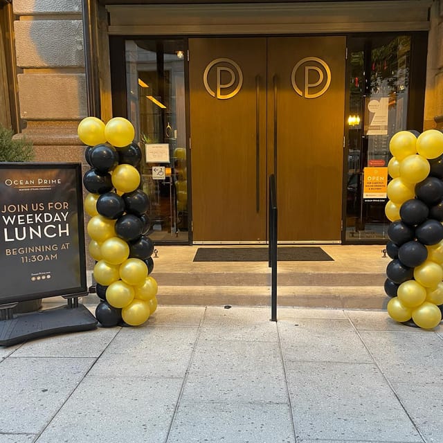 Elegant Arlington Room entrance with black and gold balloon arches for upscale lunch events.
