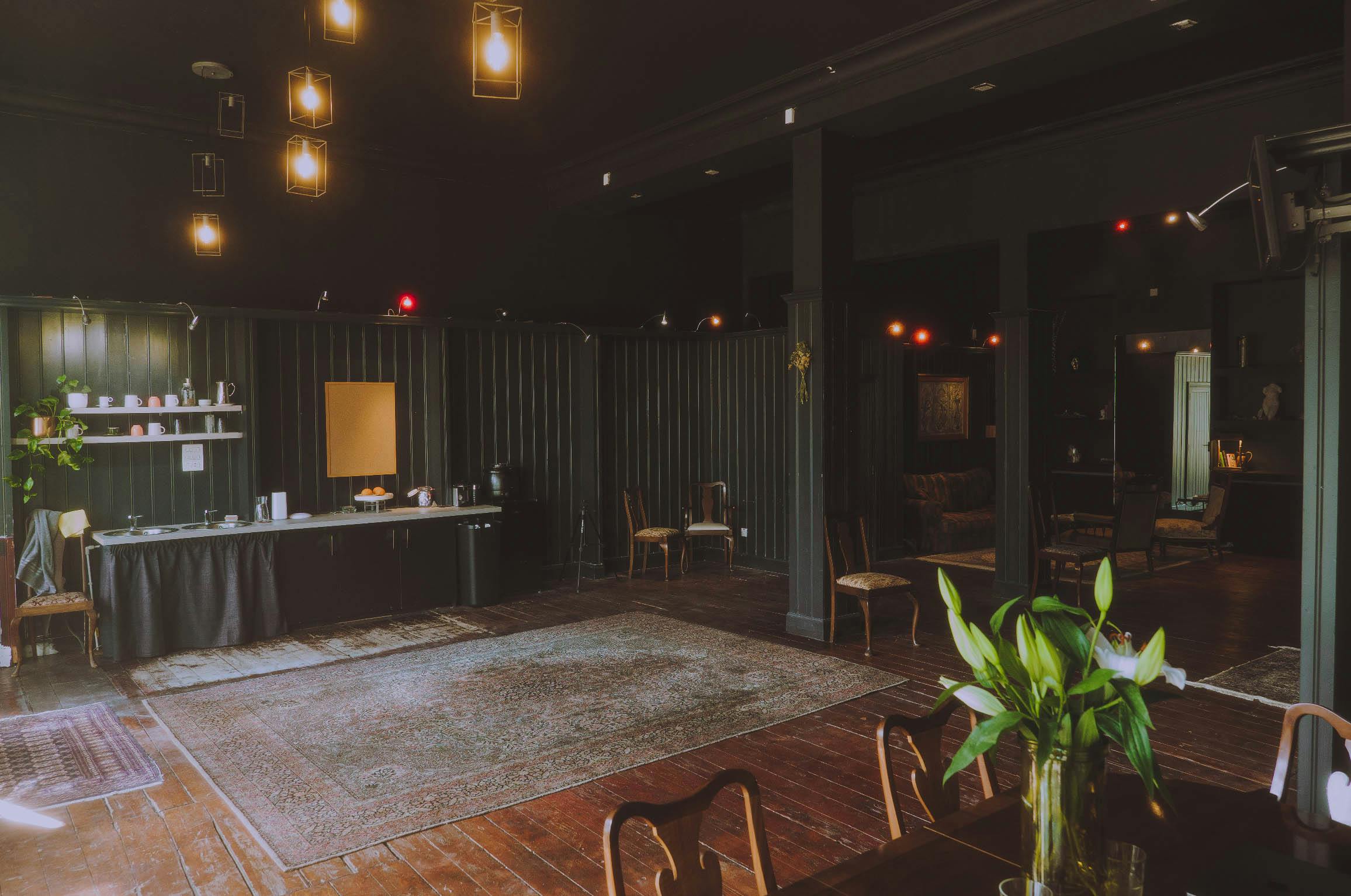 Versatile event space in GRAVITAS with dark walls, ideal for meetings and gatherings.