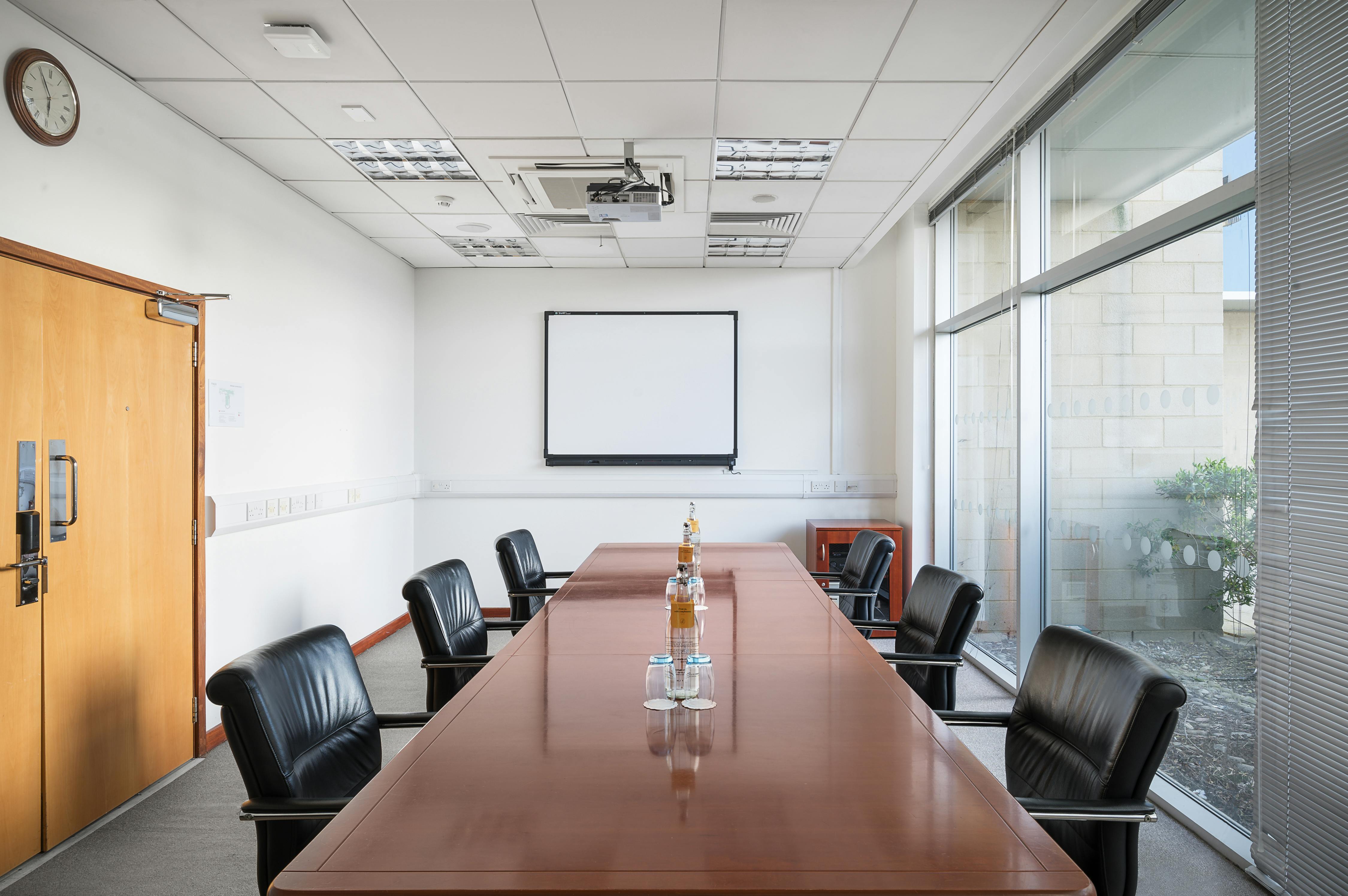 Modern conference room in Voco Reading with wooden table, ideal for meetings and presentations.