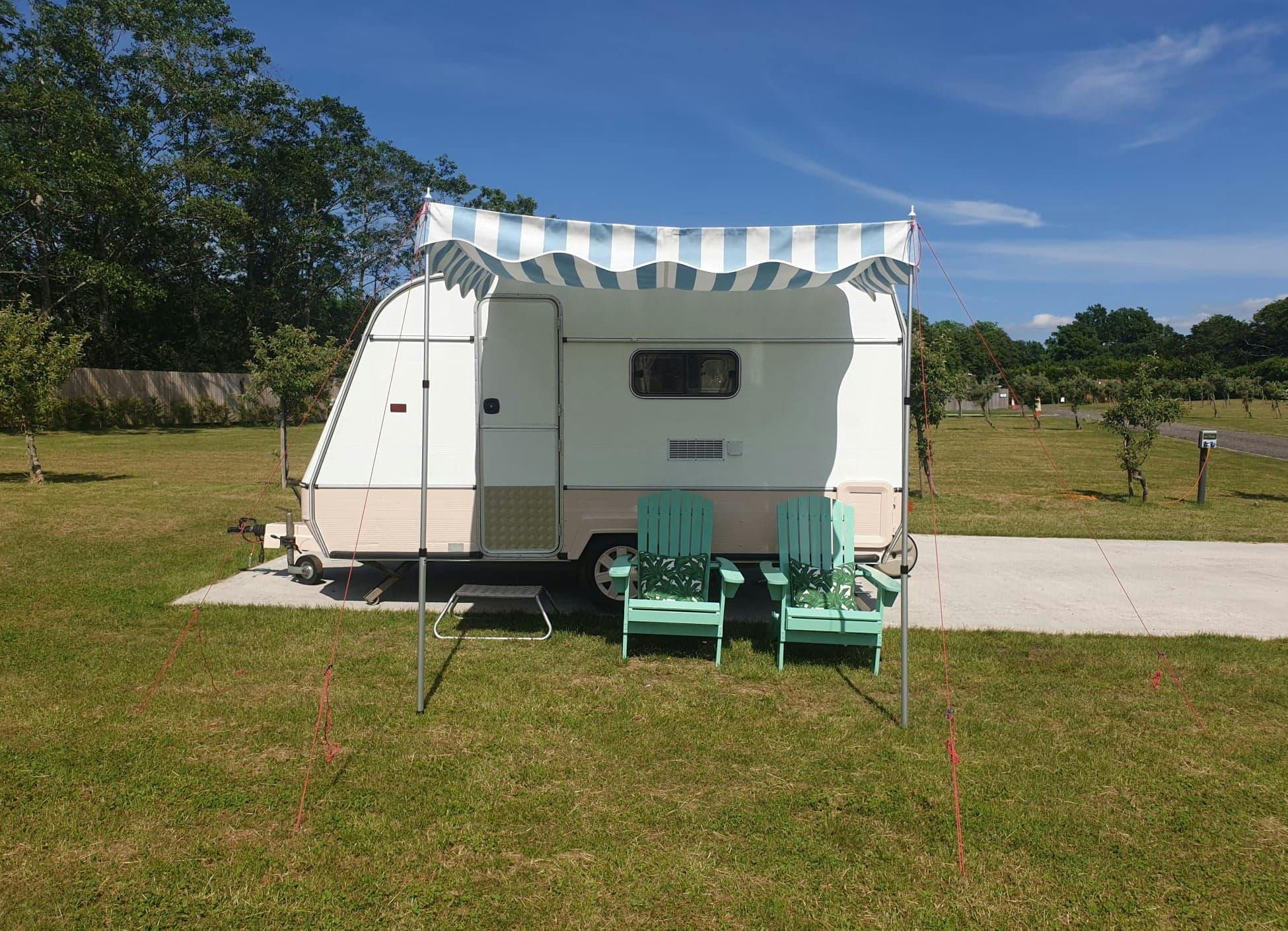 Vintage caravan with green chairs for unique outdoor events and gatherings.