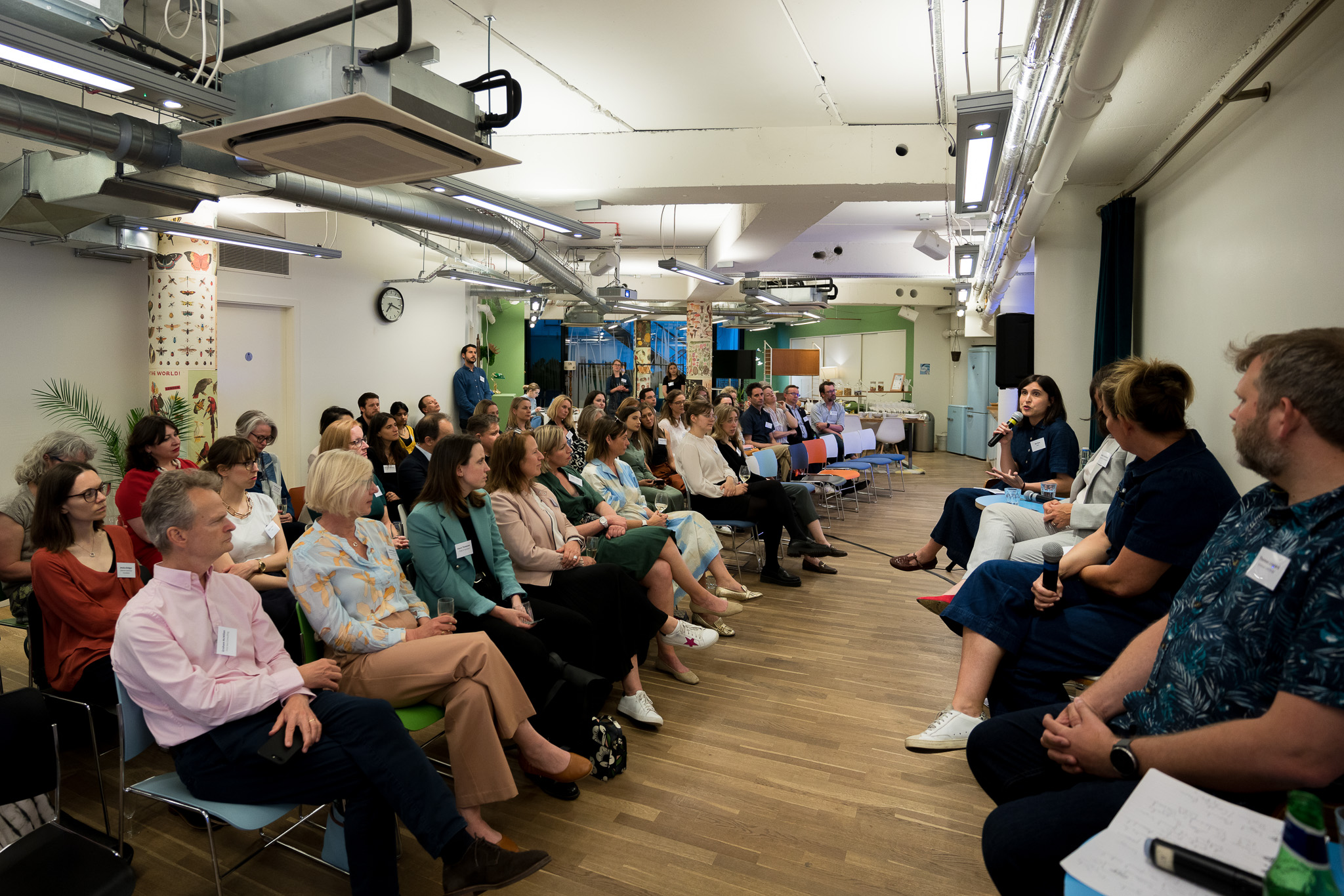 Panel discussion in modern event space with engaged audience and natural light. - Banner