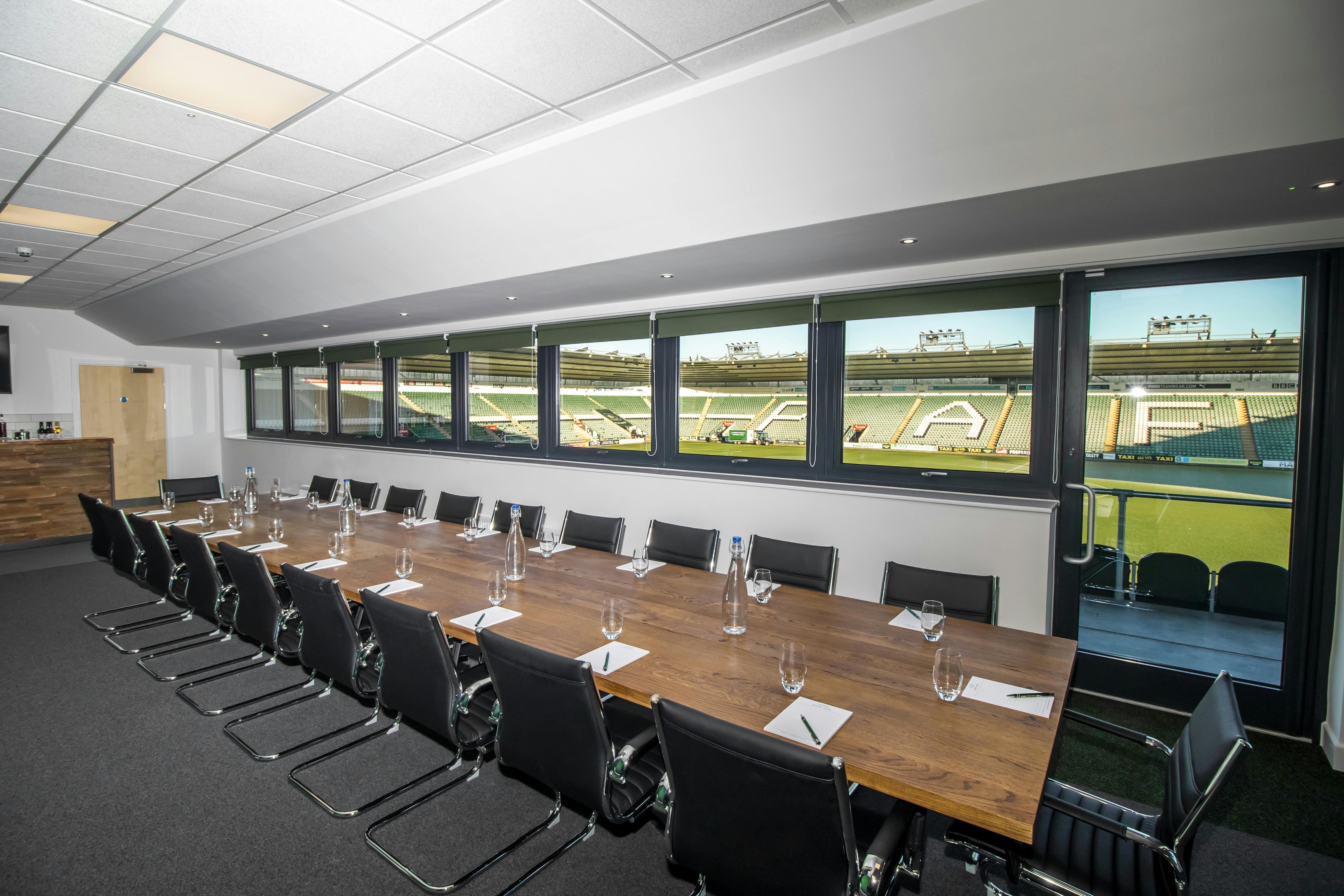 Modern meeting room in Home Park Stadium with wooden table, ideal for corporate events.