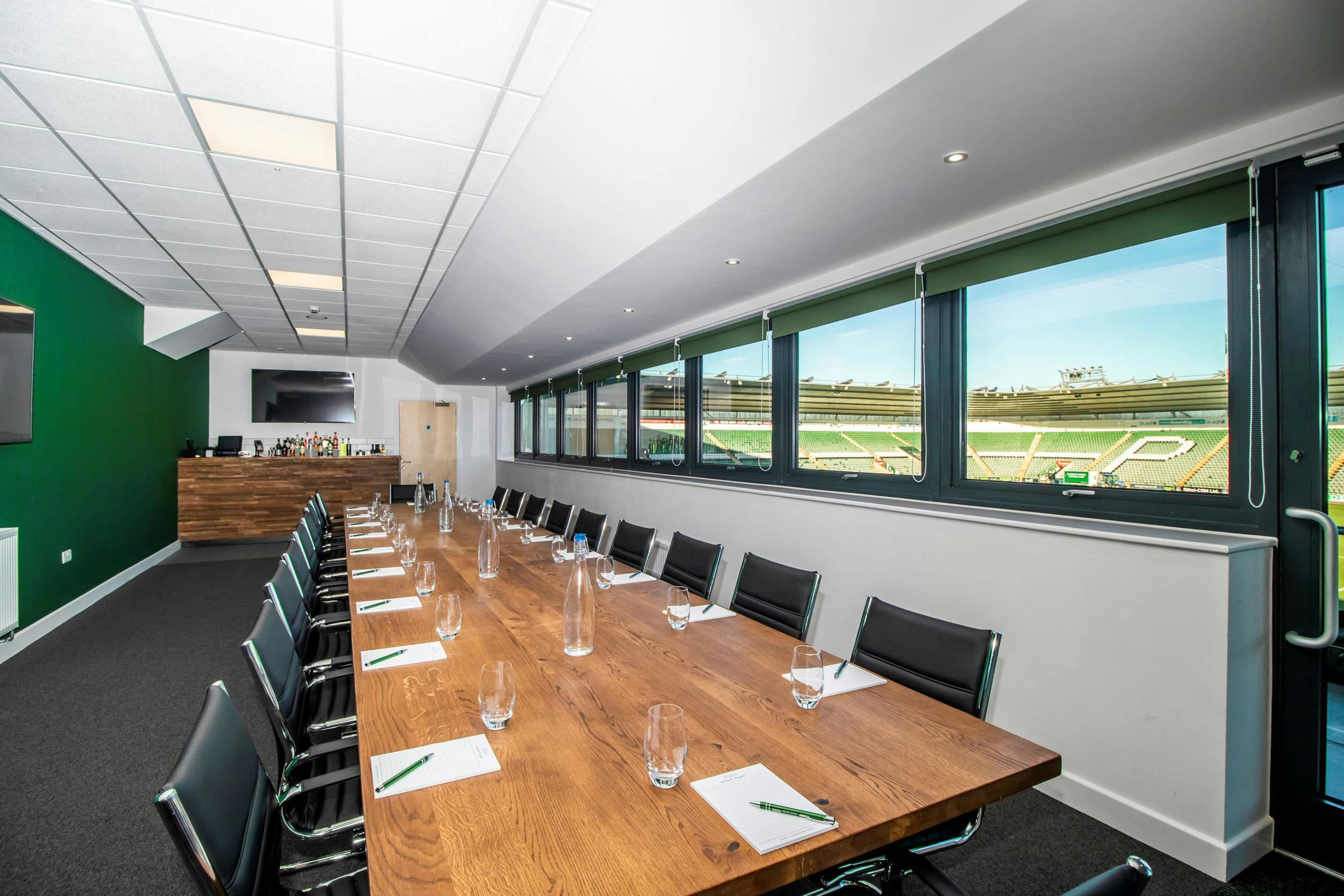 Modern meeting room at Home Park Stadium with a long wooden table and natural light.