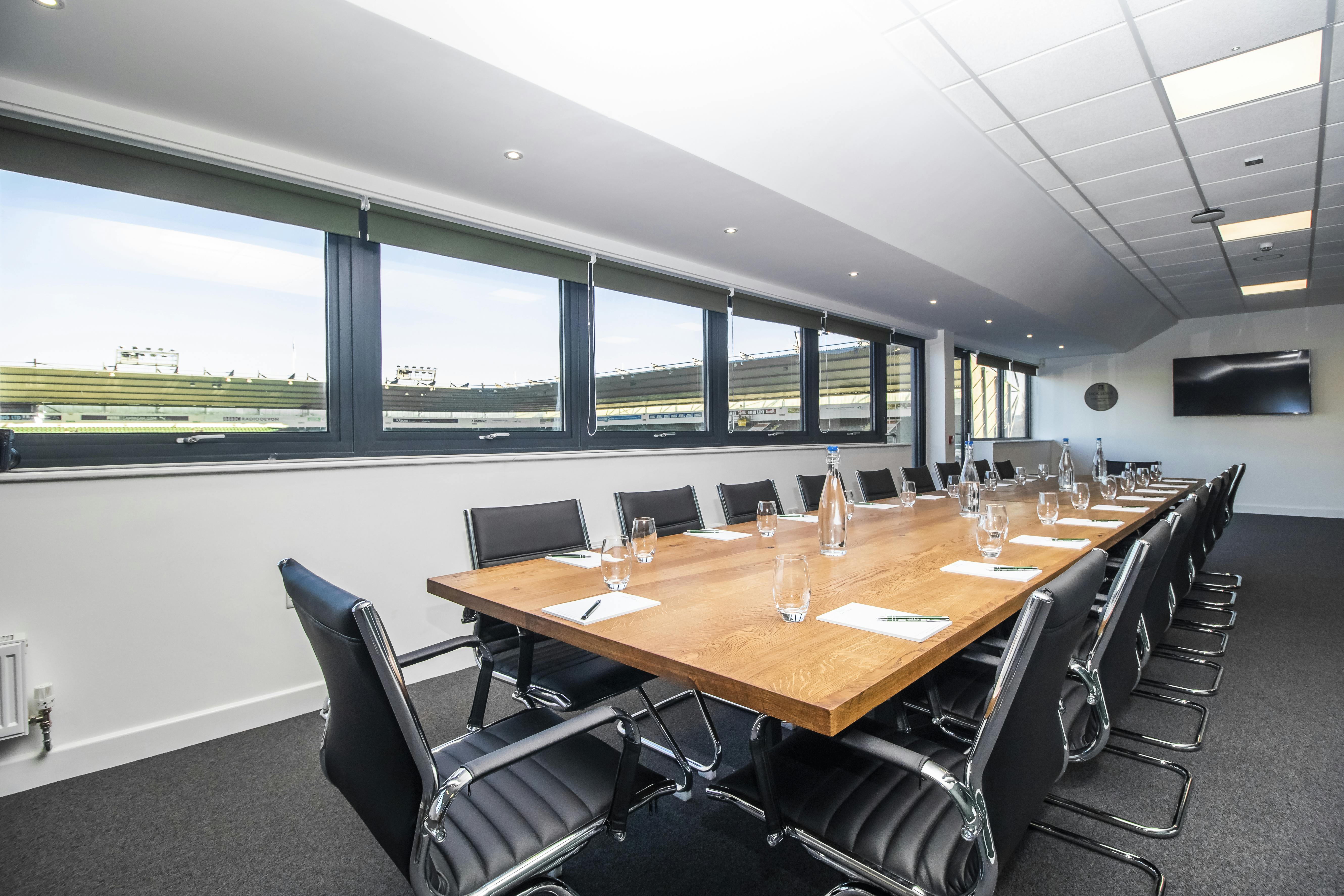 Modern conference room in Home Park Stadium with large wooden table for corporate events.