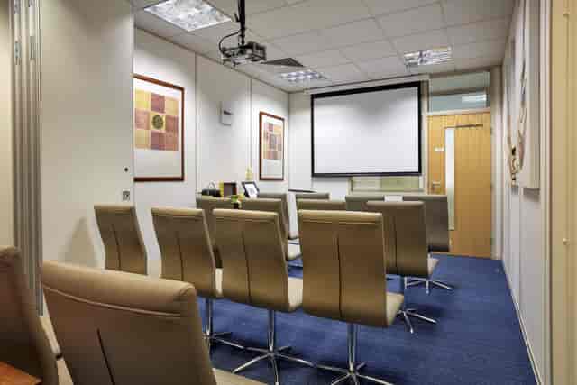 Beethoven 1 meeting room with modern seating and large projection screen for events.