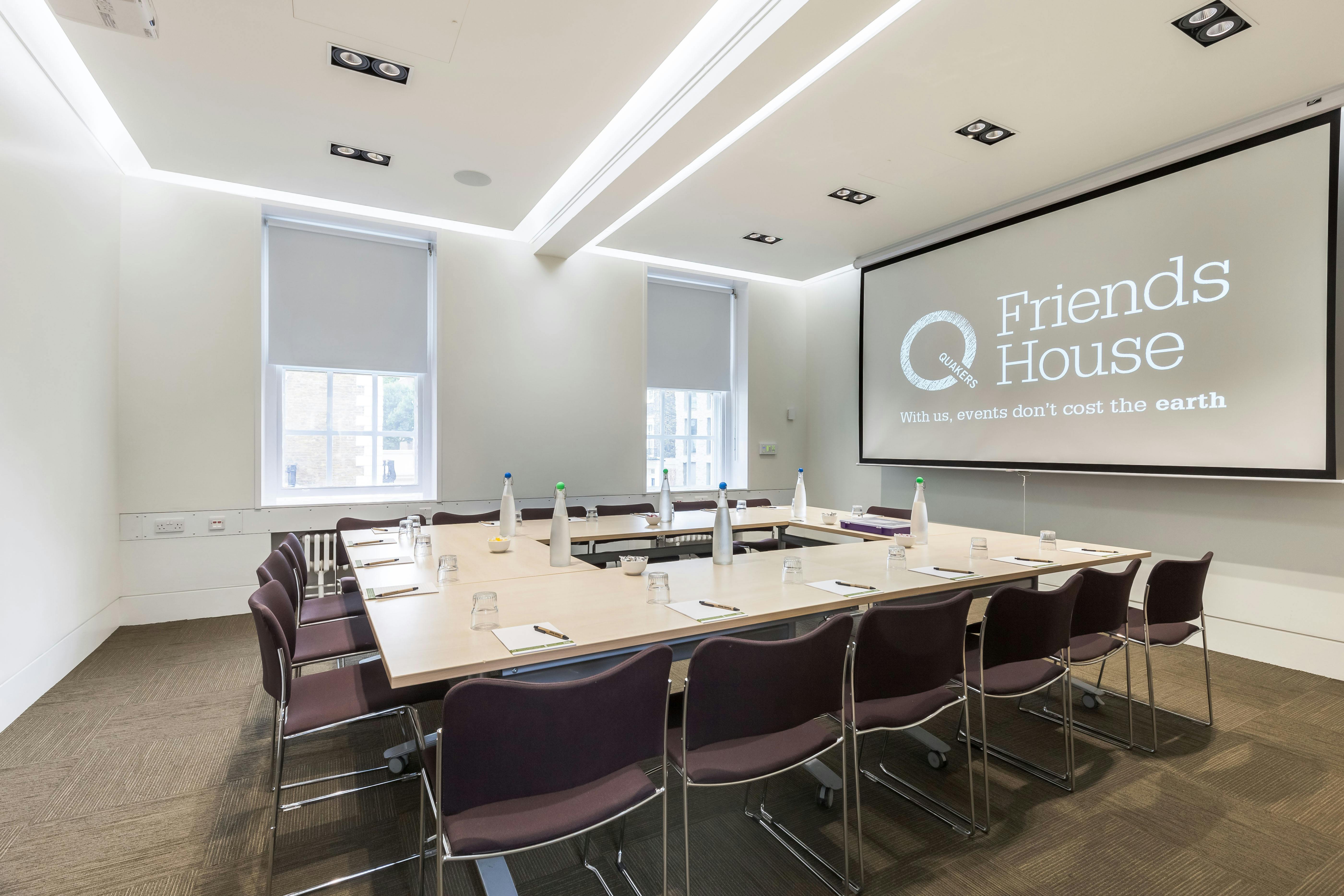 Modern meeting room with large screen, ideal for corporate workshops and gatherings.