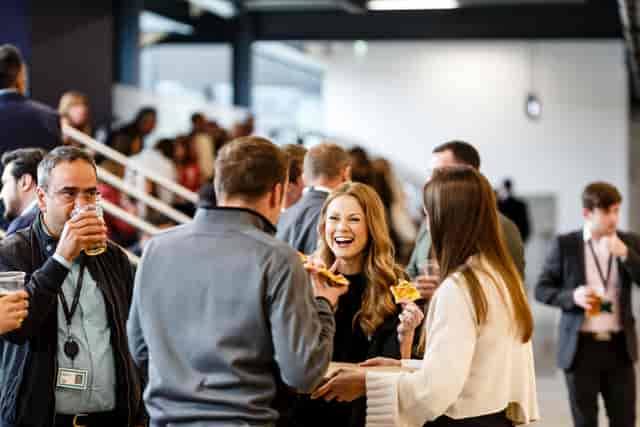 Vibrant networking event at Tottenham Hotspur Stadium with attendees enjoying refreshments.