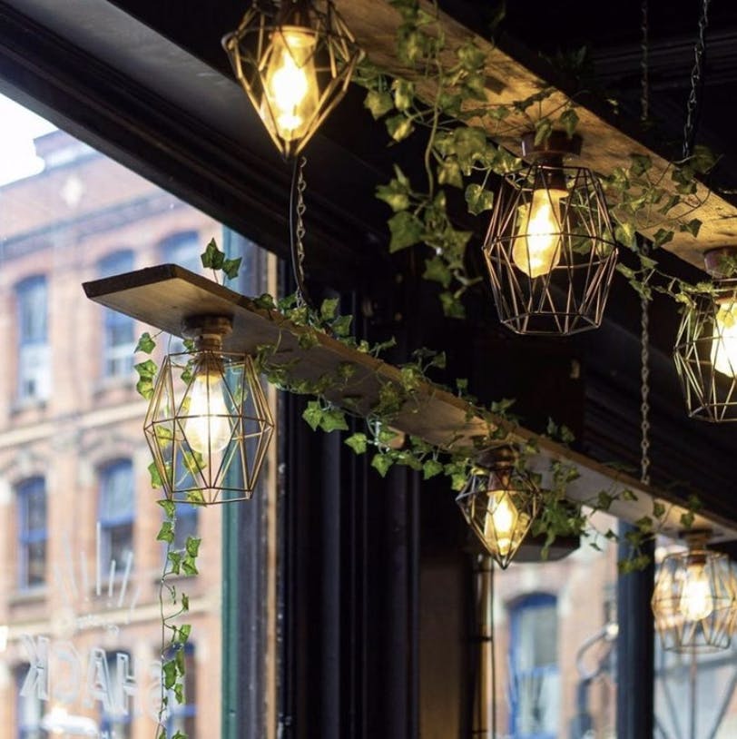 Stylish Main Bar with geometric pendant lights and greenery, perfect for events.