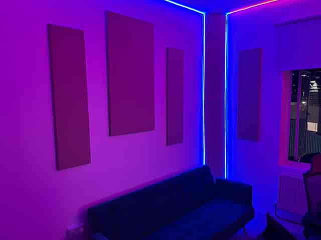 Modern music recording studio with blue couch, perfect for networking events and meetings.